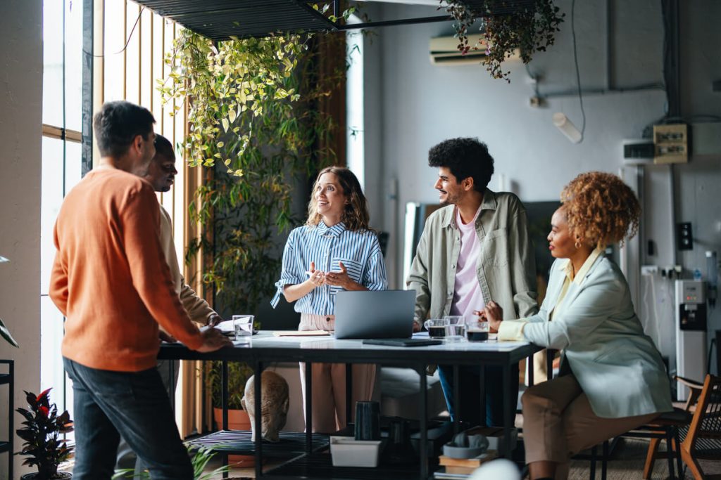 Colaboradores em volta de uma mesa de trabalho.