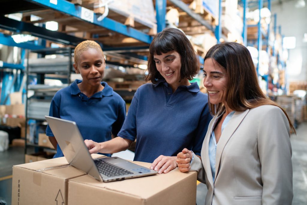 Mulher em um galpão de distribuidor olhando para o computador e sua campanha de incentivo