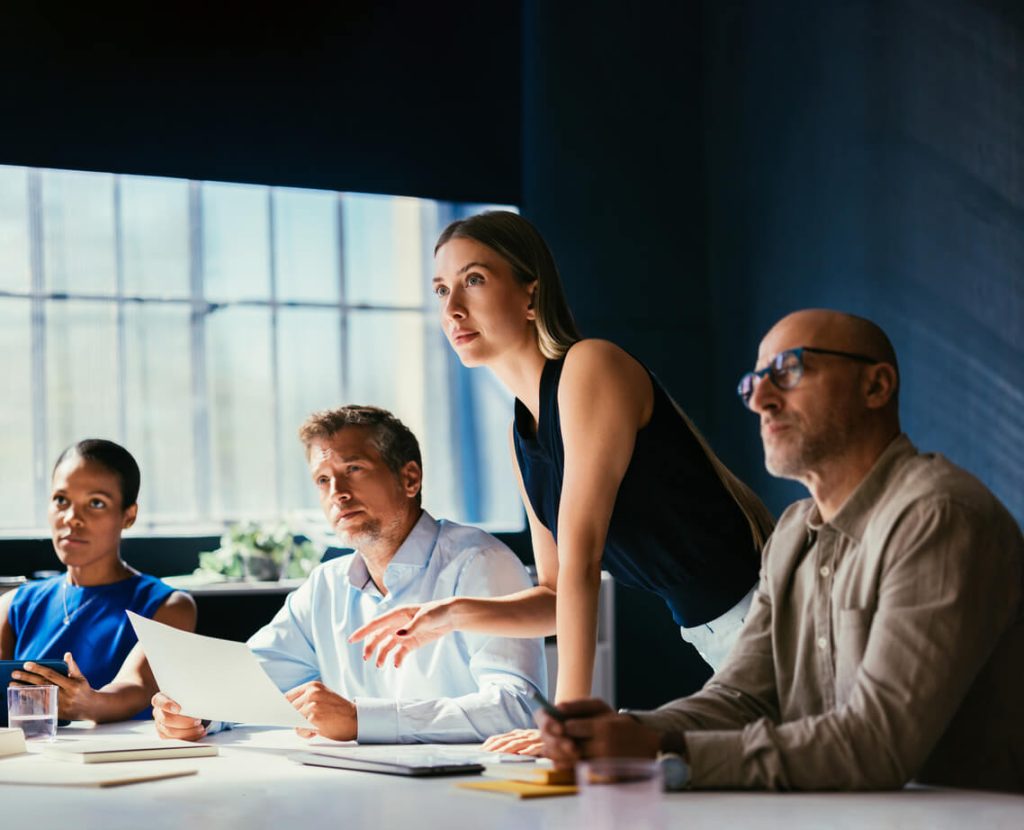 Pessoas em uma sala de reunião prestando atenção em alguém (recompensa para equipes comerciais)